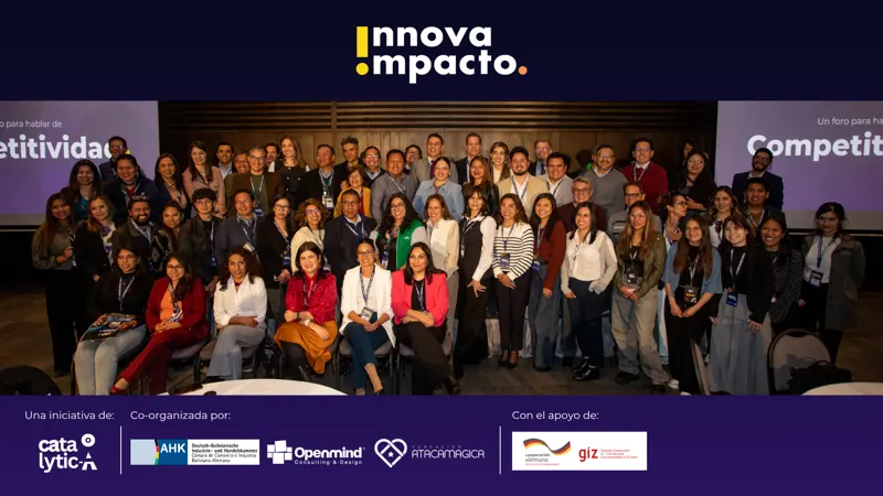 Foto grupal de participantes frente a la pantalla de InnovaImpacto